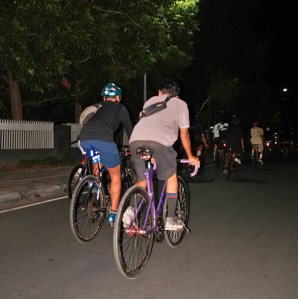 Riders on fixed-gear bikes on a city street at night